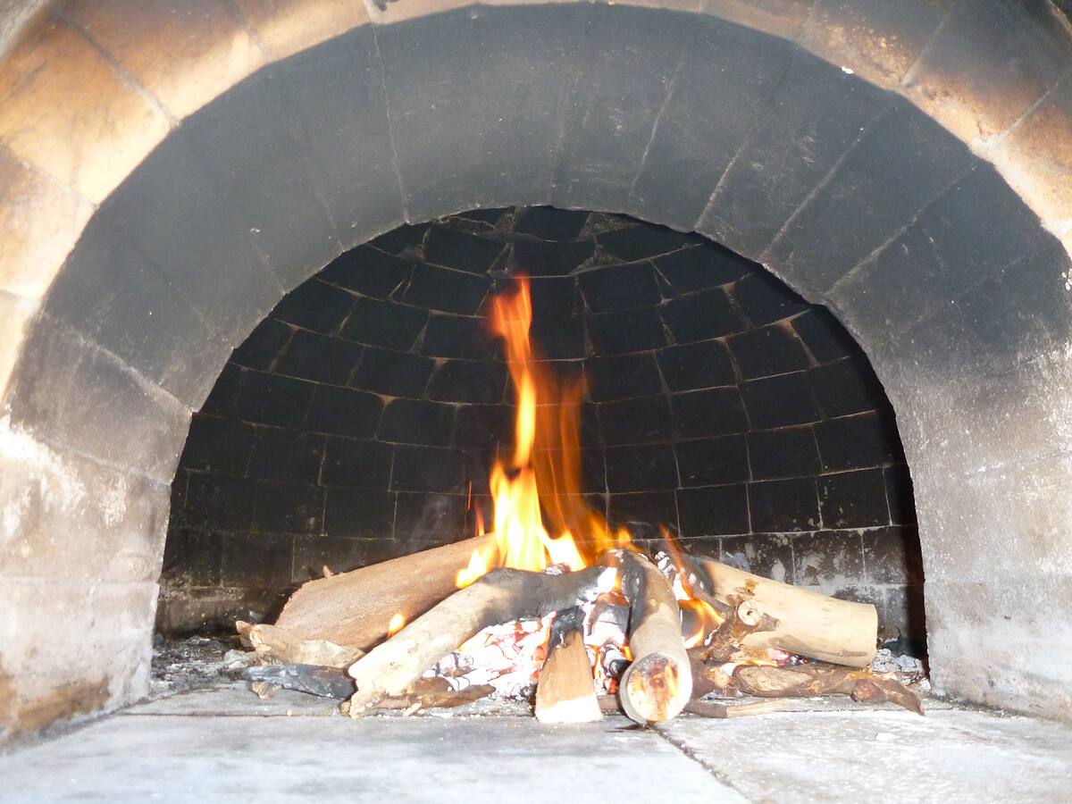 Close-up of a fire inside a handmade firebrick pizza oven