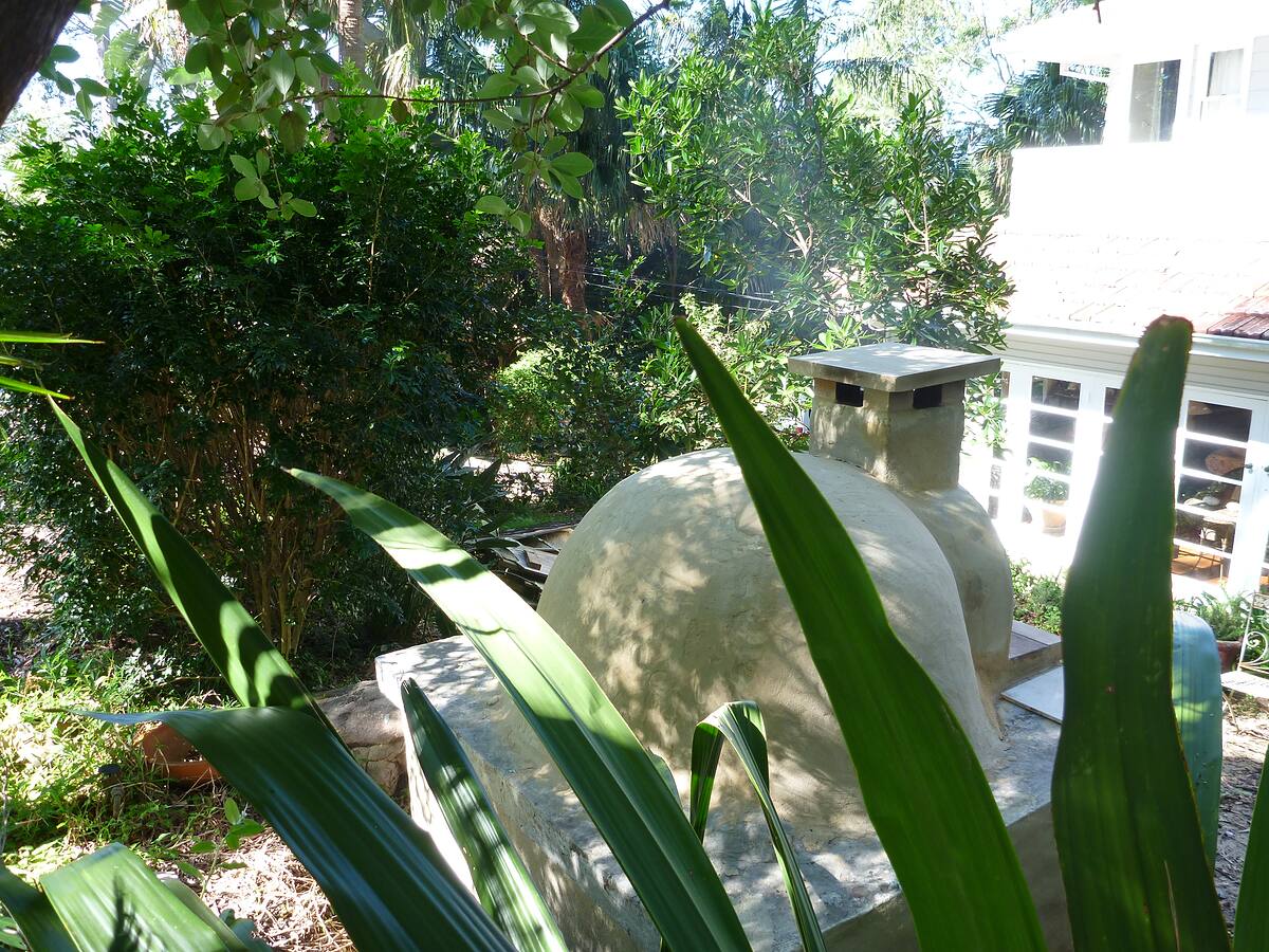 Rendered dome wood-fired oven surrounded by tropical planting