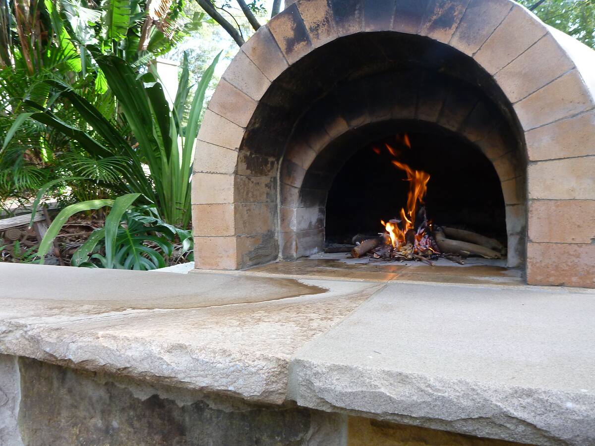Wood-fired oven with a sandstone bench and mixed-stone base