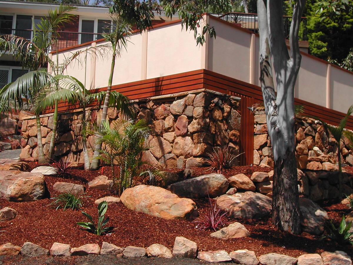 Sandstone boulder wall and tropical garden beds landscaped by nb landscapers in Cromer