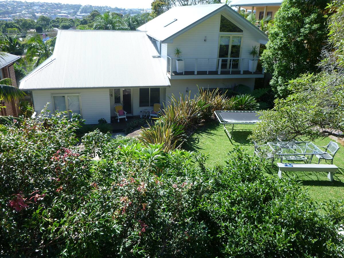 Backyard lawn and garden beds below a two-storey home