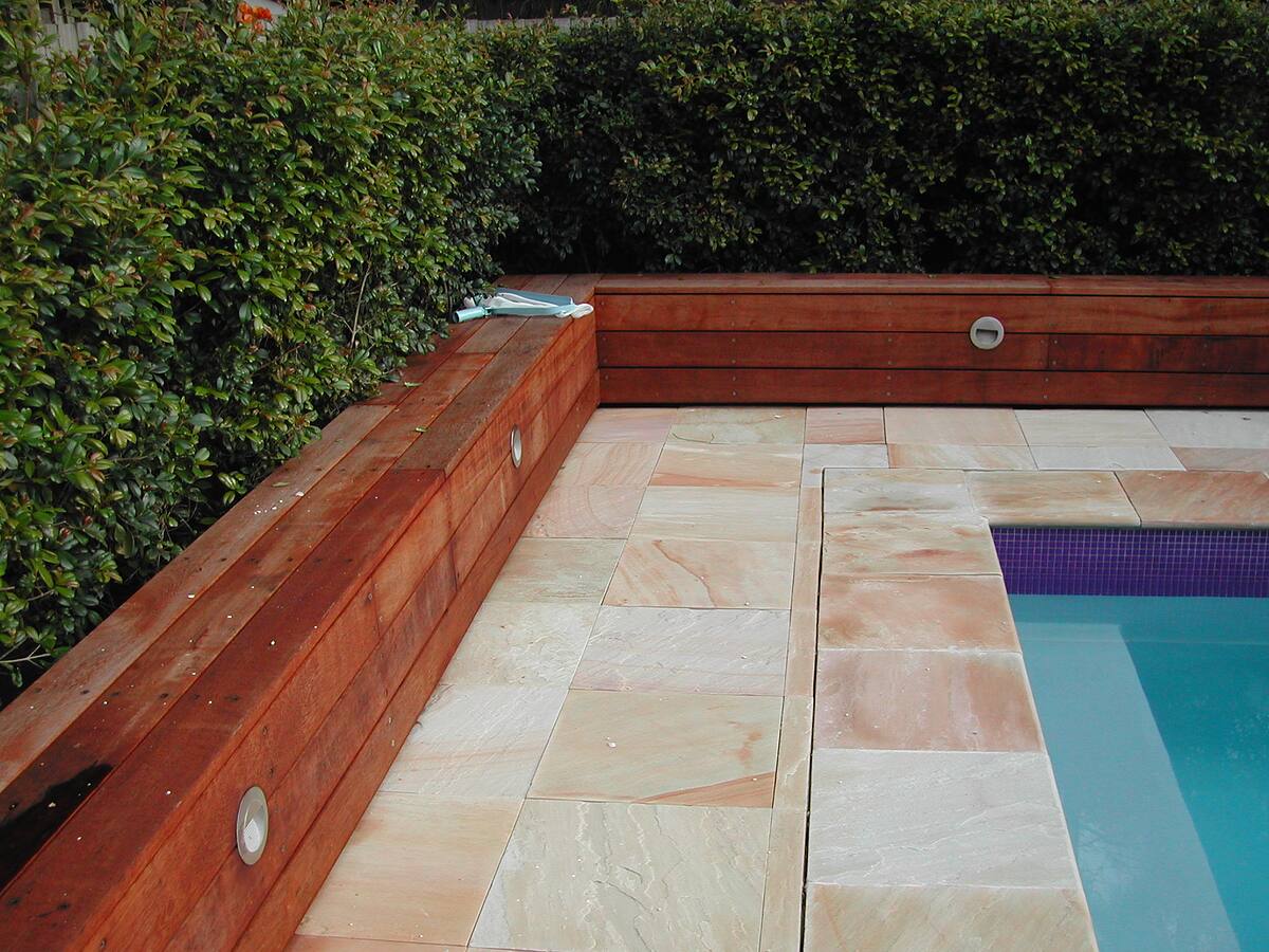 Sandstone pool surround with hardwood-clad planter walls
